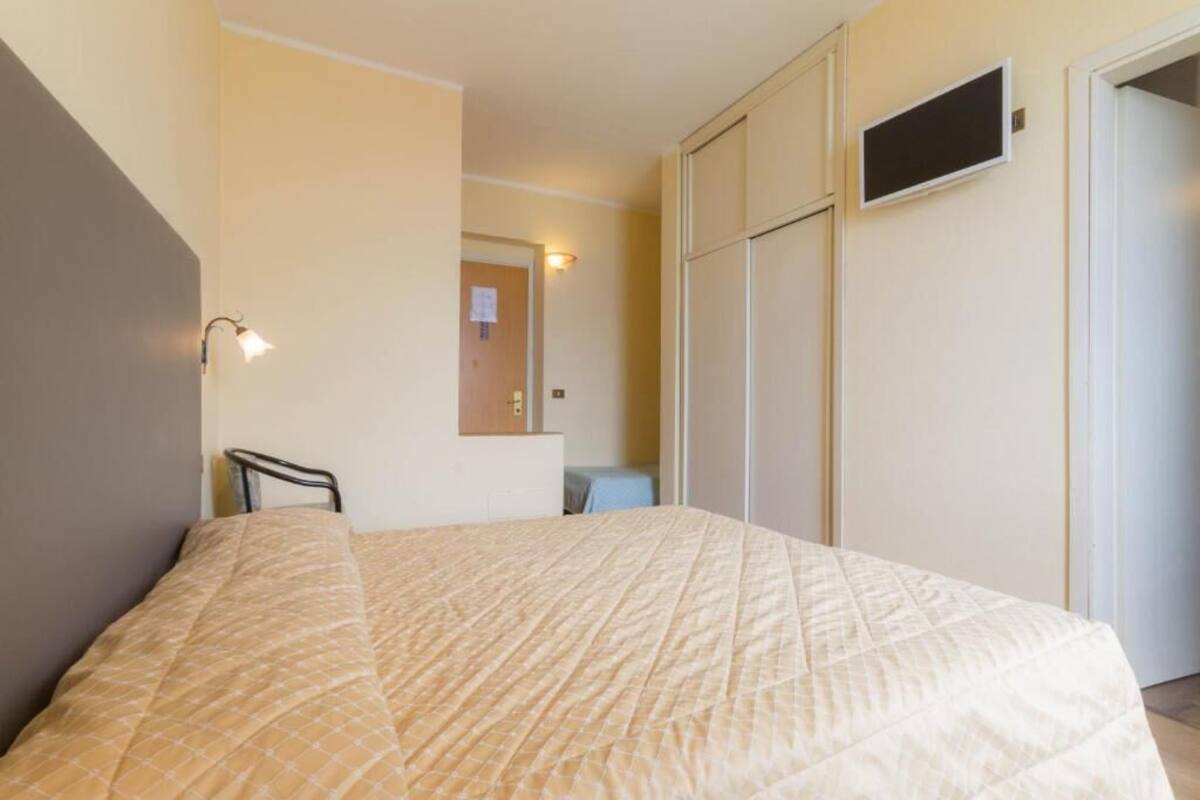 Een slaapkamer met een bed, een stoel, een bureau en een kledingkast.