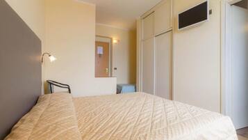 Ein Schlafzimmer mit Bett, Sessel, Schreibtisch und Kleiderschrank.