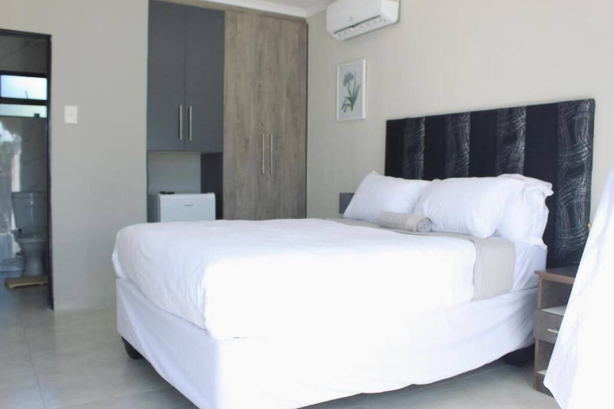 Un dormitorio con cama, armario, una mesita y aire acondicionado.