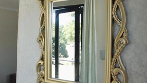 A mirror with an ornate gold frame mounted on a white wall. - Malkhon Guesthouse (Newcastle)