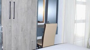 A bedroom with a bed, a chair, a wardrobe, and a mirror. - Malkhon Guesthouse (Newcastle)