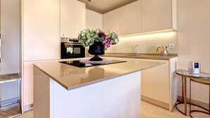 A modern kitchen with a central island, a built-in oven, and a small table with a kettle. - Luxury 3 Bed Terraced Apt Near La Cala Beach (La Cala de Mijas)