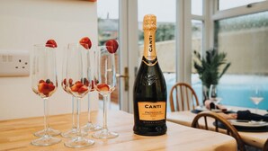 Canti Prosecco DOC 2023 -pullo pöydällä, ja sen ympärillä neljä lasia, joissa on mansikoita.