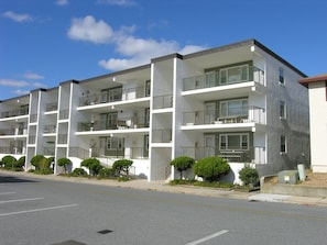 Ein mehrstöckiges Apartmenthaus mit Balkonen, einem Parkplatz und kleinen Grünflächen.