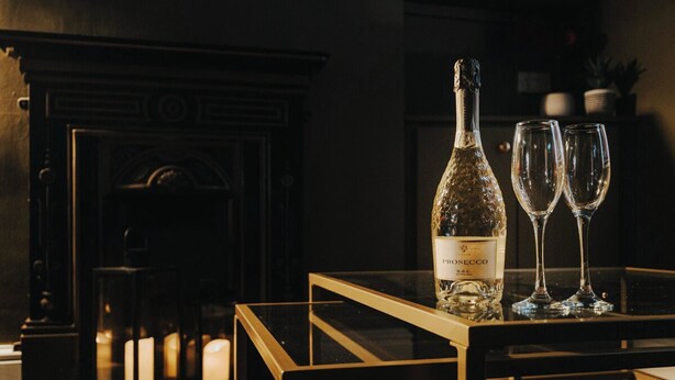 A bottle of rosé wine and two glasses on a table near a fireplace. - Spacious 2 Bed House Lancaster (Lancashire)