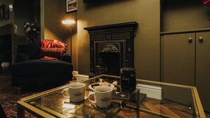 A cozy living room with a fireplace, a sofa, a coffee table with mugs, and a television mounted on the wall. - Spacious 2 Bed House Lancaster (Lancashire)