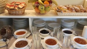 A buffet setup with fruit, pastries, and various condiments.