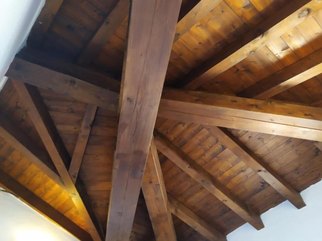 A wooden ceiling structure with beams and a sloped roof.