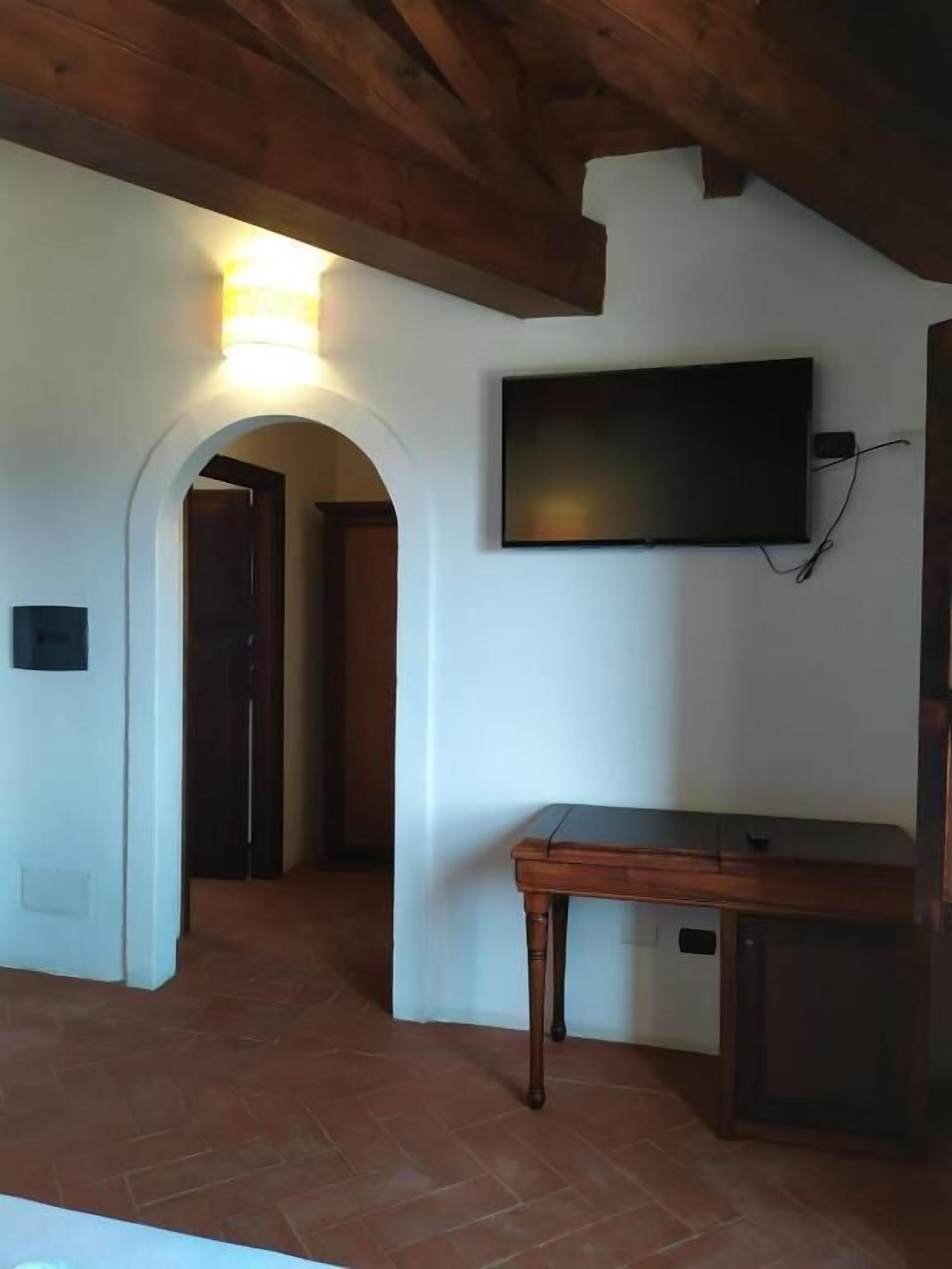 Ein Zimmer mit Holzboden, einem Wand-Fernseher, einem Holztisch und Fliesenboden.