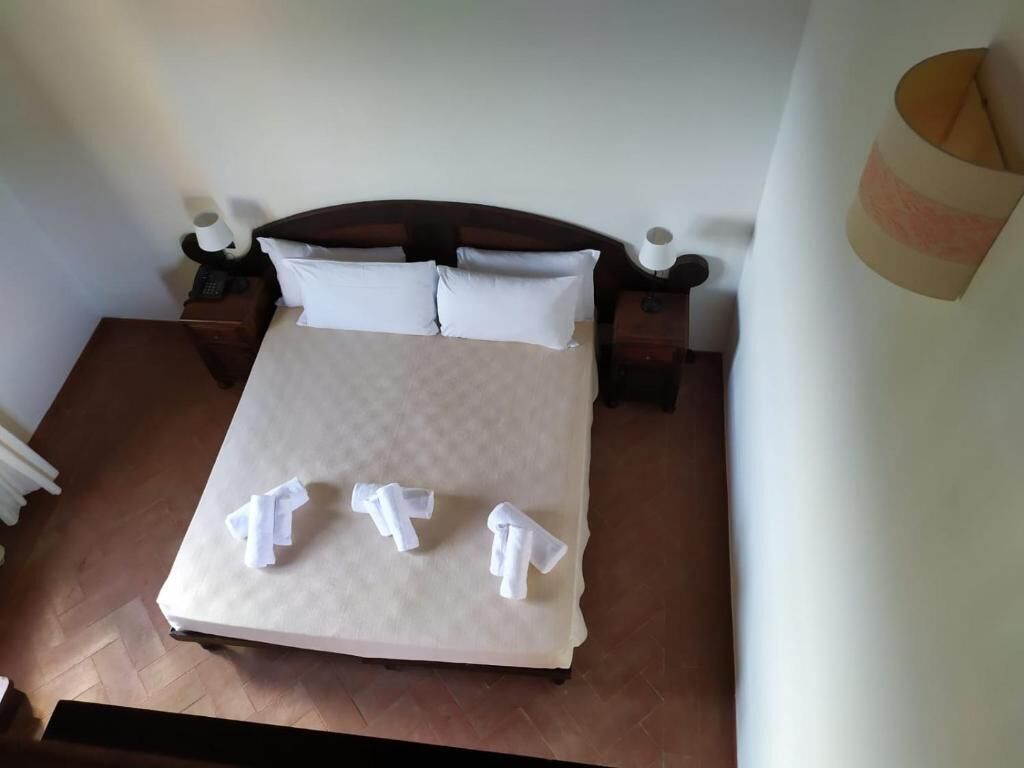 A neatly made bed with white linens, a wooden headboard, and bedside tables with lamps.