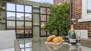 Une table en verre surmontée de croissants, une bouteille de champagne Bollinger et deux verres à vin.