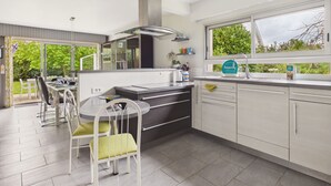 Una cocina moderna con comedor, ventanas amplias y vistas a la vegetación.