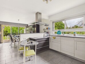 Eine moderne Küche mit Essbereich, großen Fenstern und Blick auf Grünflächen.