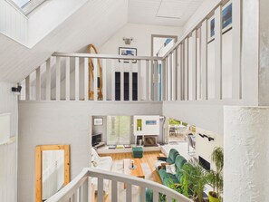 Ein mehrstöckiger Innenraum mit Treppe, Essbereich und Wohnzimmer mit Sofa und Fernseher.