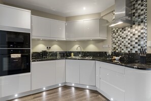 A modern kitchen with white cabinets, a black countertop, and a checkered backsplash. - Seven - La Petite Maison is a stylish, dog-friendly holiday home in Brixham (Brixham)
