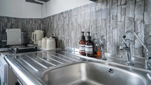 Cozinha moderna com painel de pedra, eletrodomésticos de aço inoxidável e uma pia grande.