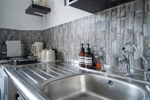 Cozinha moderna com painel de pedra, eletrodomésticos de aço inoxidável e uma pia grande.