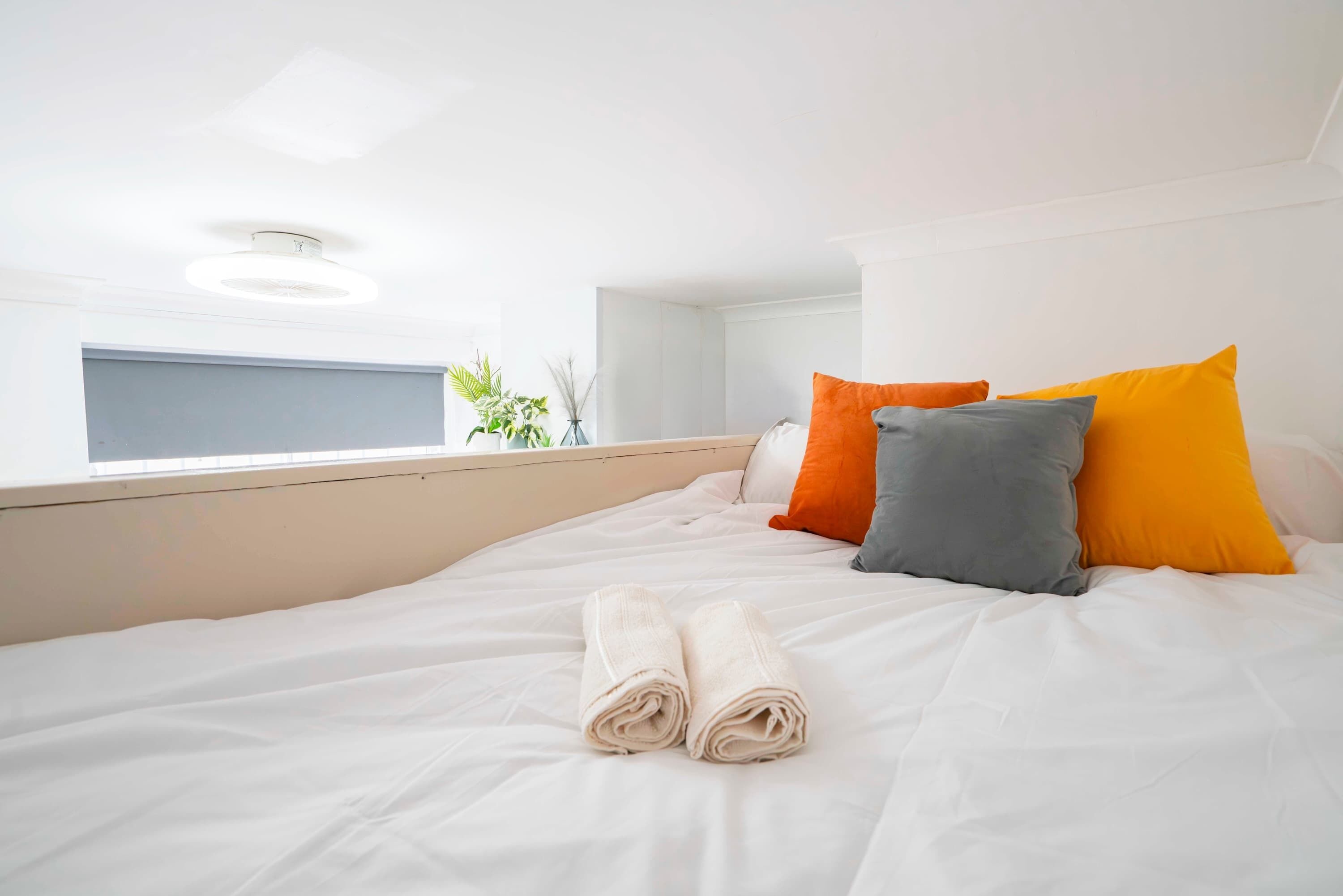 Una cama bien hecha con toallas enrolladas, una ventana con vistas y una lámpara en el techo.