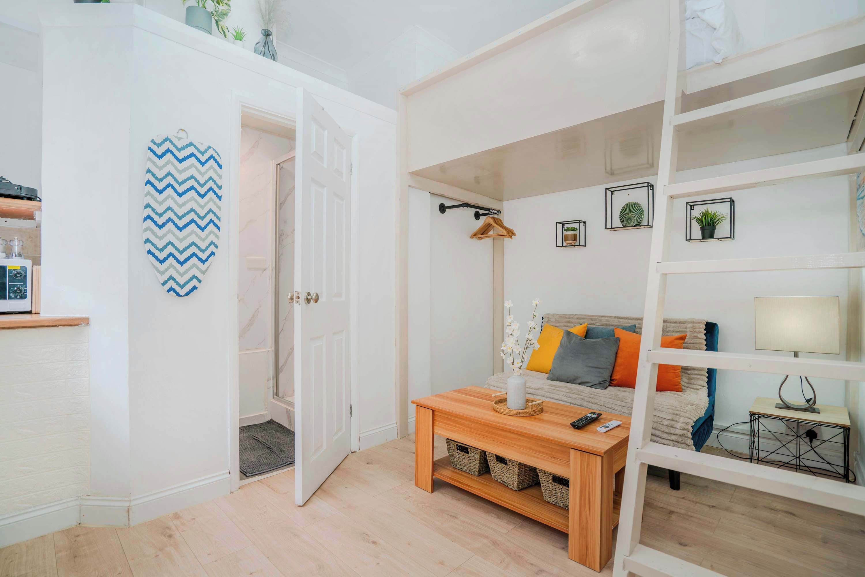 Een moderne woonkamer met een houten salontafel, een bank met kussens, een witte boekenkast en een decoratief zigzag kunstwerk aan de muur.