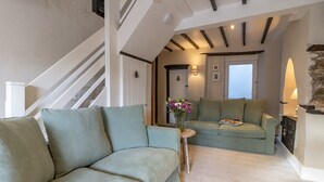 Ein Wohnzimmer mit einer Couch, einem kleinen Tisch mit einer Vase und einem Kamin.