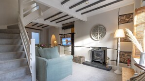 Ein modernes Wohnzimmer mit Treppe, Kamin, Fernseher und einer Wanddekoration.