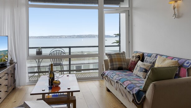 A room with a balcony, a sofa, a table, and a TV. - Seaside Rendezvous is a bright, modern three-bedroom townhouse in Brixham (Brixham)