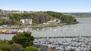A marina with numerous boats, a coastal town with buildings, and a hilly backdrop. - Seaside Rendezvous is a bright, modern three-bedroom townhouse in Brixham (Brixham)