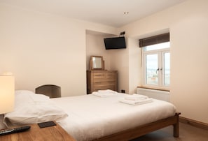 A hotel room with a bed, a TV mounted on the wall, a dresser, and a window with a view. - Upper Anzac is a stylish and spacious three bedroom holiday apartment in Brixham (Brixham)