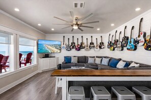 Ein Wohnzimmer mit Fernseher, einer Couch, einem Couchtisch und einer Wand voller Gitarren.