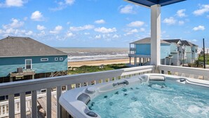Een bubbelbad op een balkon met uitzicht op strand en zee.