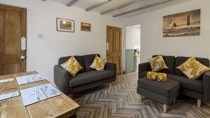 A room with two sofas, a wooden table, and a herringbone floor. - Pisces Cottage, a delightful Grade II listed two bedroom cottage in Brixham (Brixham)
