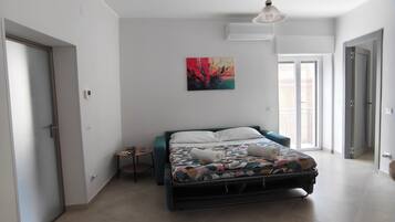A bedroom with a bed, a painting, a ceiling light, and a window.