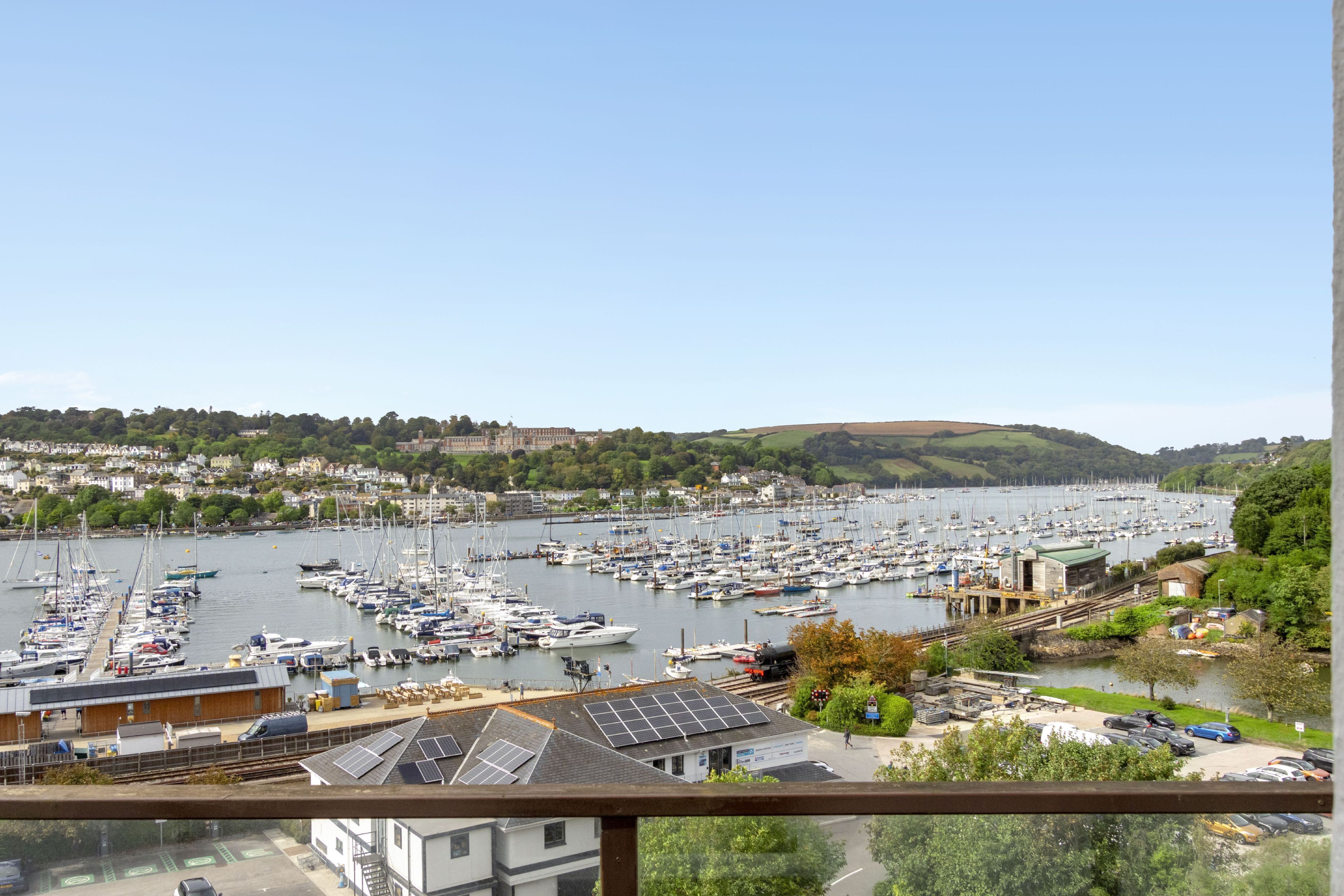 A marina with numerous boats docked, surrounded by residential buildings and greenery.