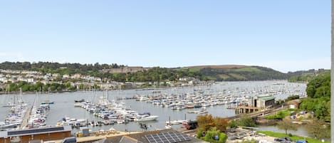 A marina with numerous boats docked, surrounded by residential buildings and greenery.