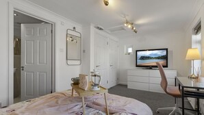 Una camera d'albergo con un letto, una scrivania con una sedia, una televisione e una finestra vista spiaggia.