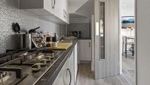 Una cucina moderna con piano cottura in acciaio inossidabile, forno a microonde e un bancone in legno.