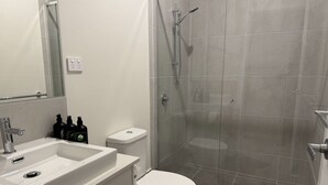 Un baño con ducha, inodoro, lavabo y espejo.