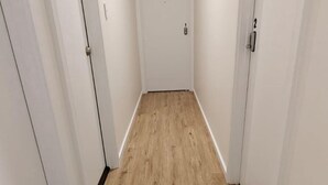 Un pasillo estrecho con suelo de madera y paredes blancas.