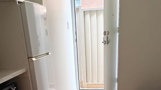 Un pasillo estrecho con un refrigerador, un microondas y un banco.