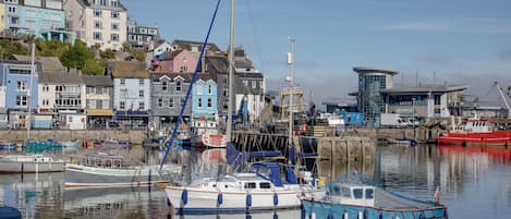 A harbor with boats docked, a building with a sign, and a clear sky.