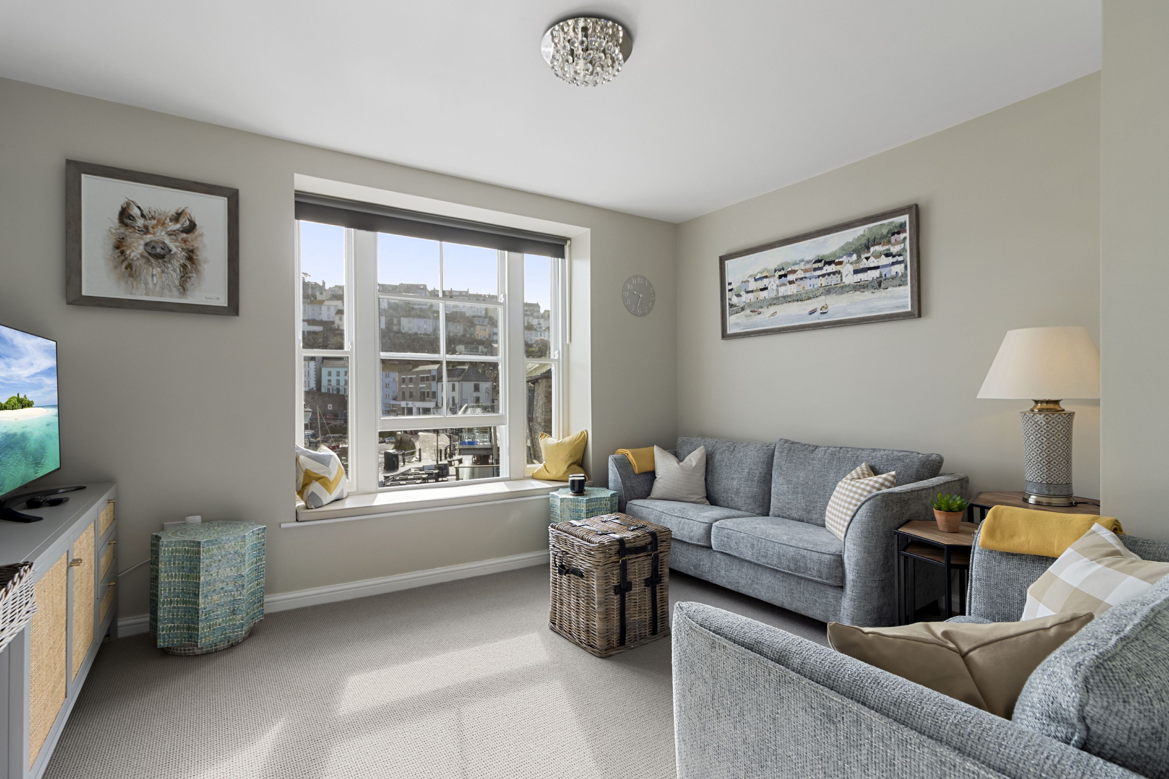 A living room with a sofa, a television, a window with a city view, and a lamp.