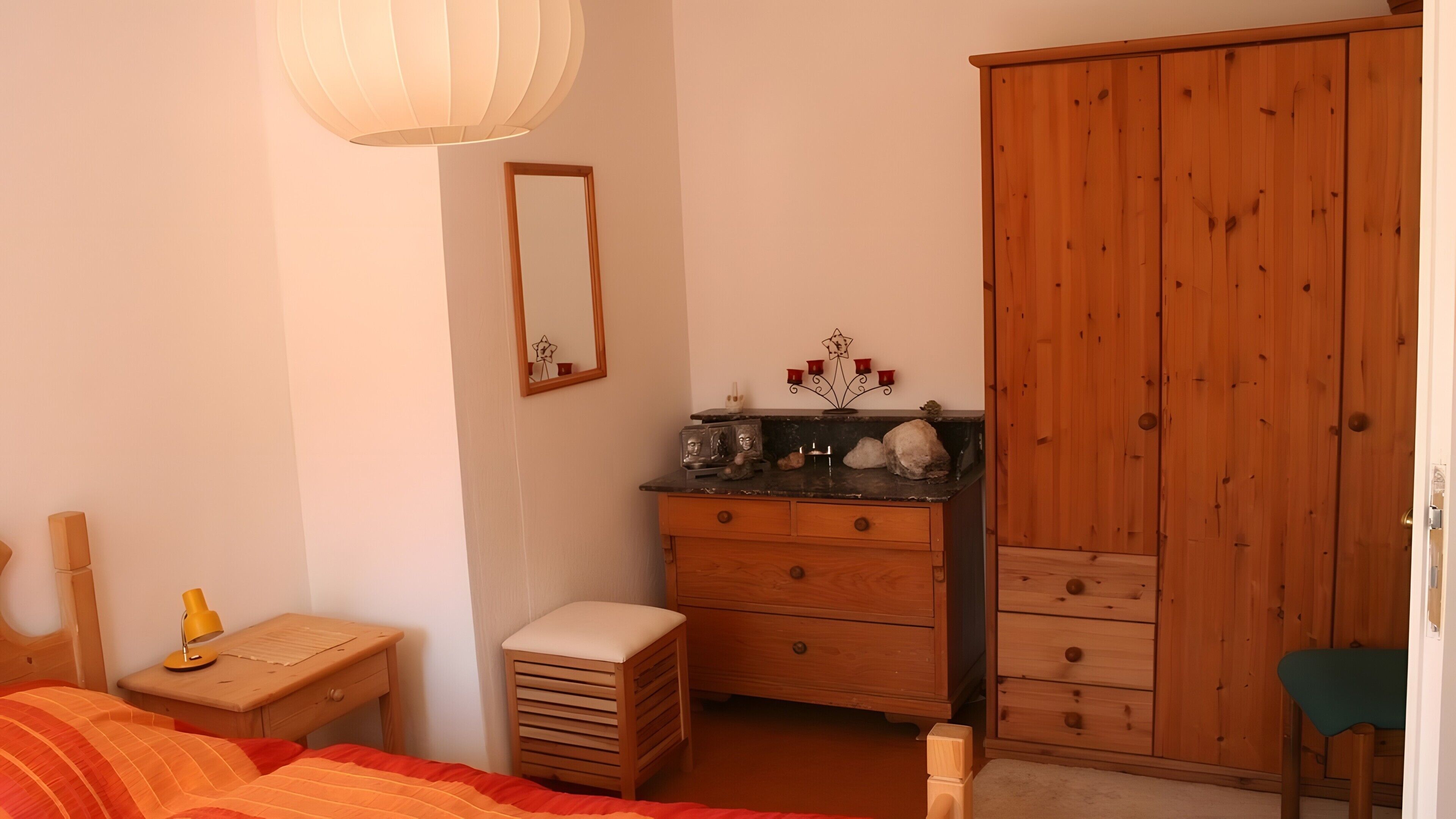 Une chambre à coucher comprenant un lit, une table de chevet, une commode, un miroir et une armoire.