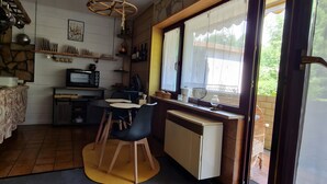 A kitchen with a microwave, stove, and dining area with chairs and a table.