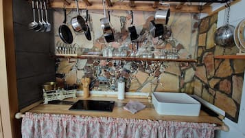 Una cocina rústica con ollas colgantes, un salpicadero de piedra y un mantel estampado.