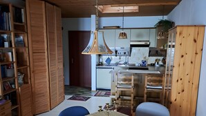 Ruokailutila, jossa on neljälle katettu ruokapöytä, kirjahylly ja taustalla keittiö.