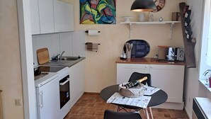 A compact kitchen with a built-in oven, a sink, and a dining area with a table and chairs.