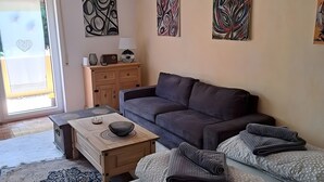 A living room with a sofa, a coffee table, a lamp, and artwork on the walls.