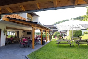 An outdoor patio area with tables and chairs, a covered seating area, and a view of the surrounding landscape. - Hotel Tiefenhagen Sauerland (Lennestadt)