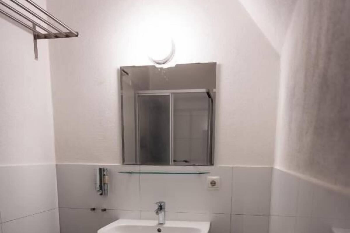 A small bathroom with a white sink, mirror, and toilet.