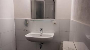 A small bathroom with a white sink, mirror, and toilet.